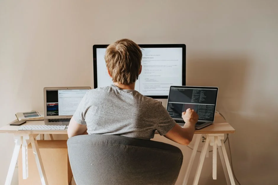 Two monitors on a desk, displaying web design in a contemporary office environment.