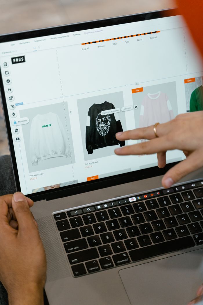 Close-up view of hands using a shopping website on a laptop screen indoors.
